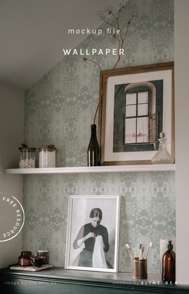 Corner of a room showing a section of a lower wooden cabinet with a framed art and personal objects on top of it. Above the cabinet there is a shelf with a framed picture, a glass pot with cotton inside and a glass bottle with a dry branch of a plant. On the wall behind it a wallpaper by Aline Bea.