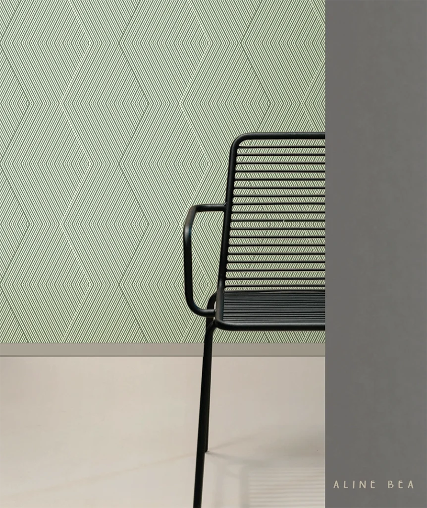 A modern metal dark chair half hidden by a wall. Behind the chair there's a geometric and minimalist wallpaper by Aline Bea applied to the wall.