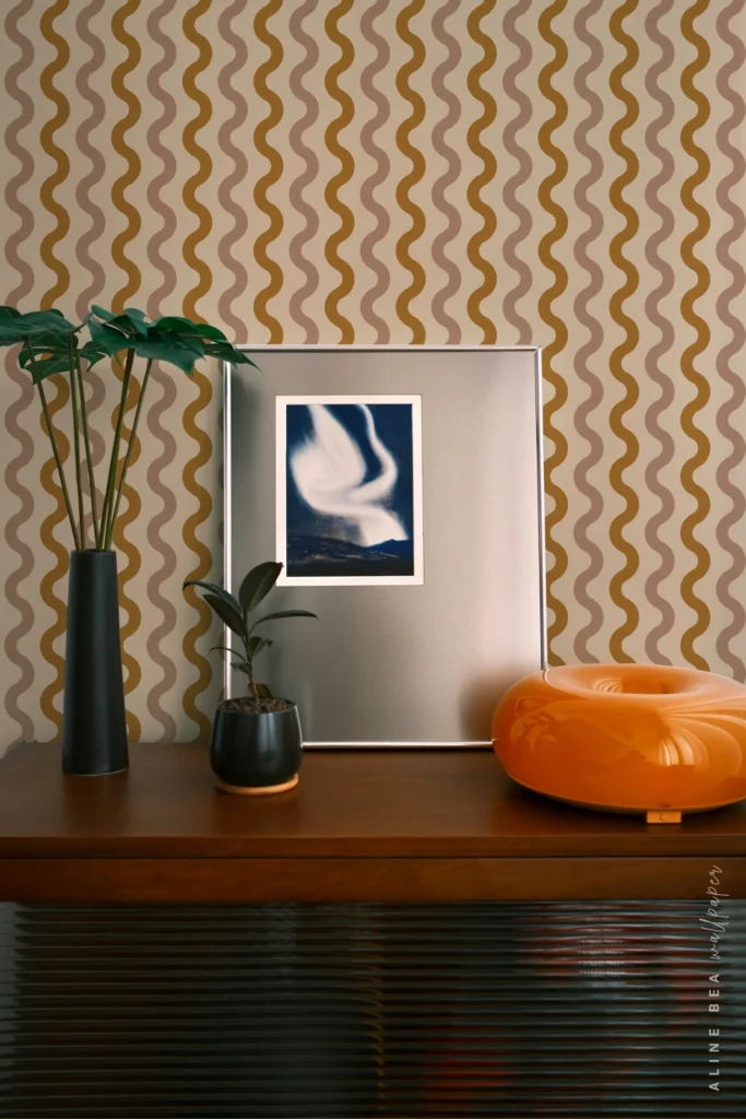 Mustard and taupe wavy vertical stripe wallpaper behind a mid-century credenza